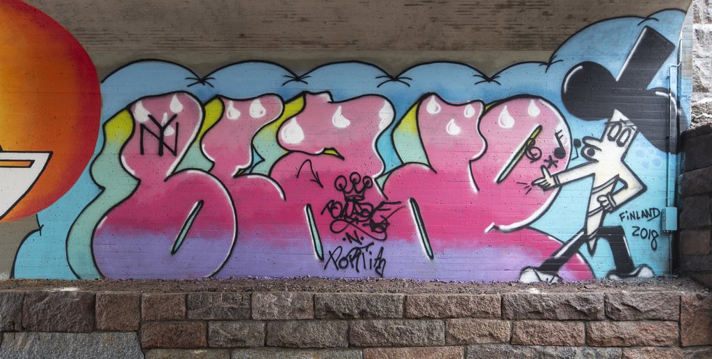 Värikäs graffiti alikulkusillan betoniseinässä. Graffitissa lukee tyylitelty BLADE ja oikeassa laidassa on humoristinen ja viheltävä puukko.