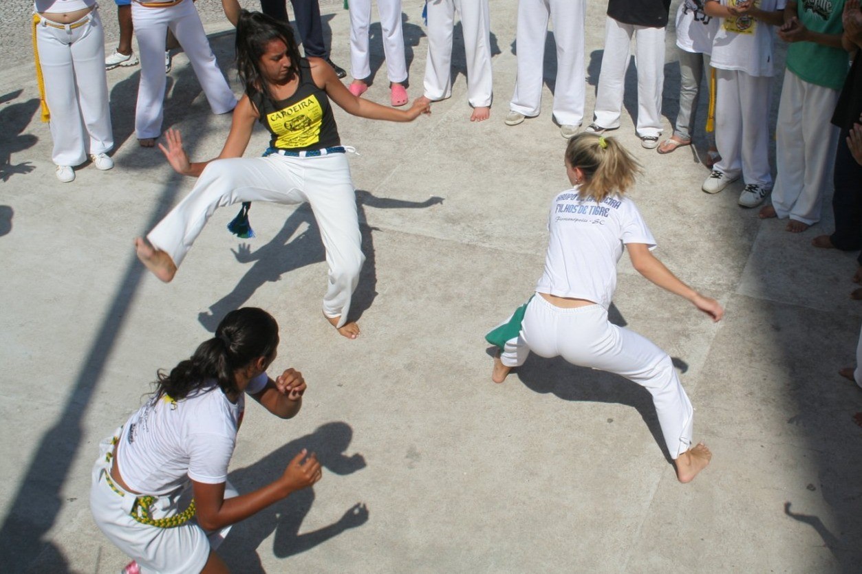 Kolme nuorta tekemässä Capoeiran liikkeitä.