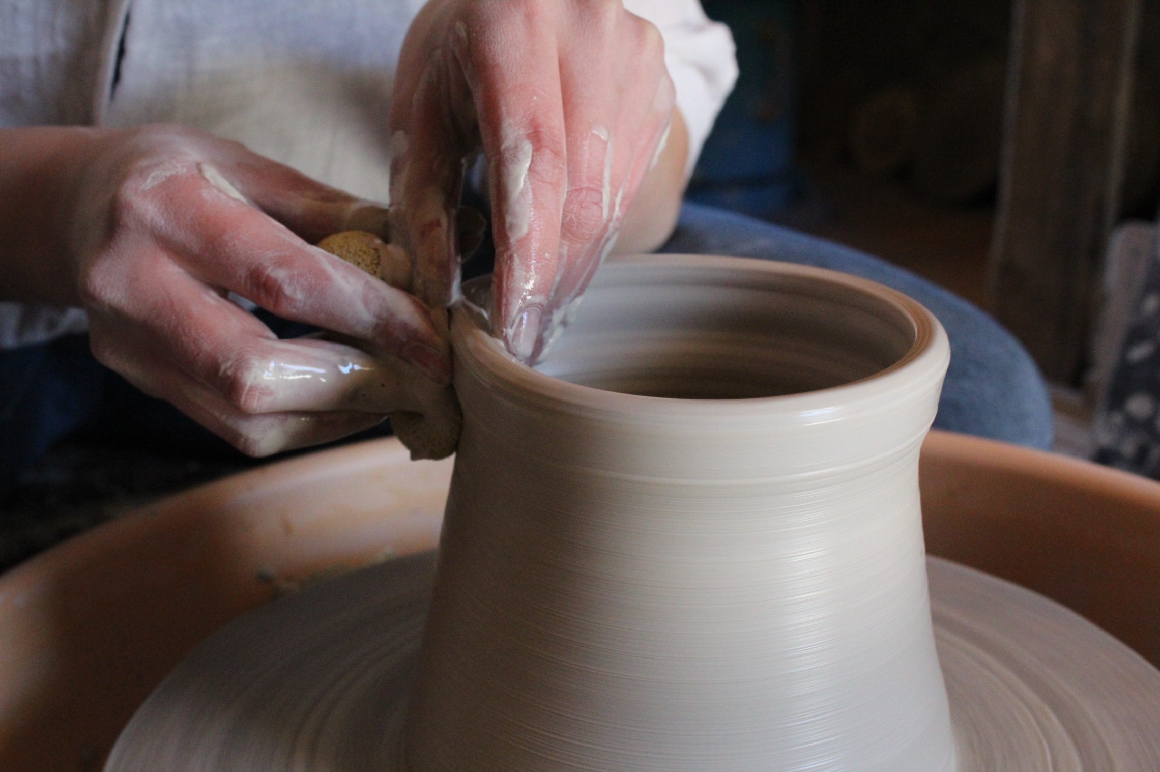 Kädet savessa keramikka-astia valmistuu ja dreija pyörii.