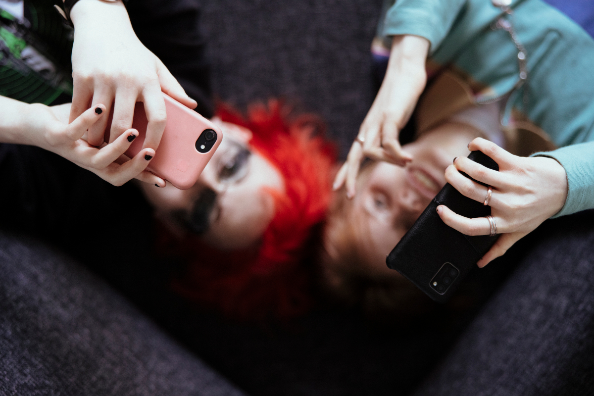 Kaksi nuorta makaa selällään ja katsovat kännyköihinsä.