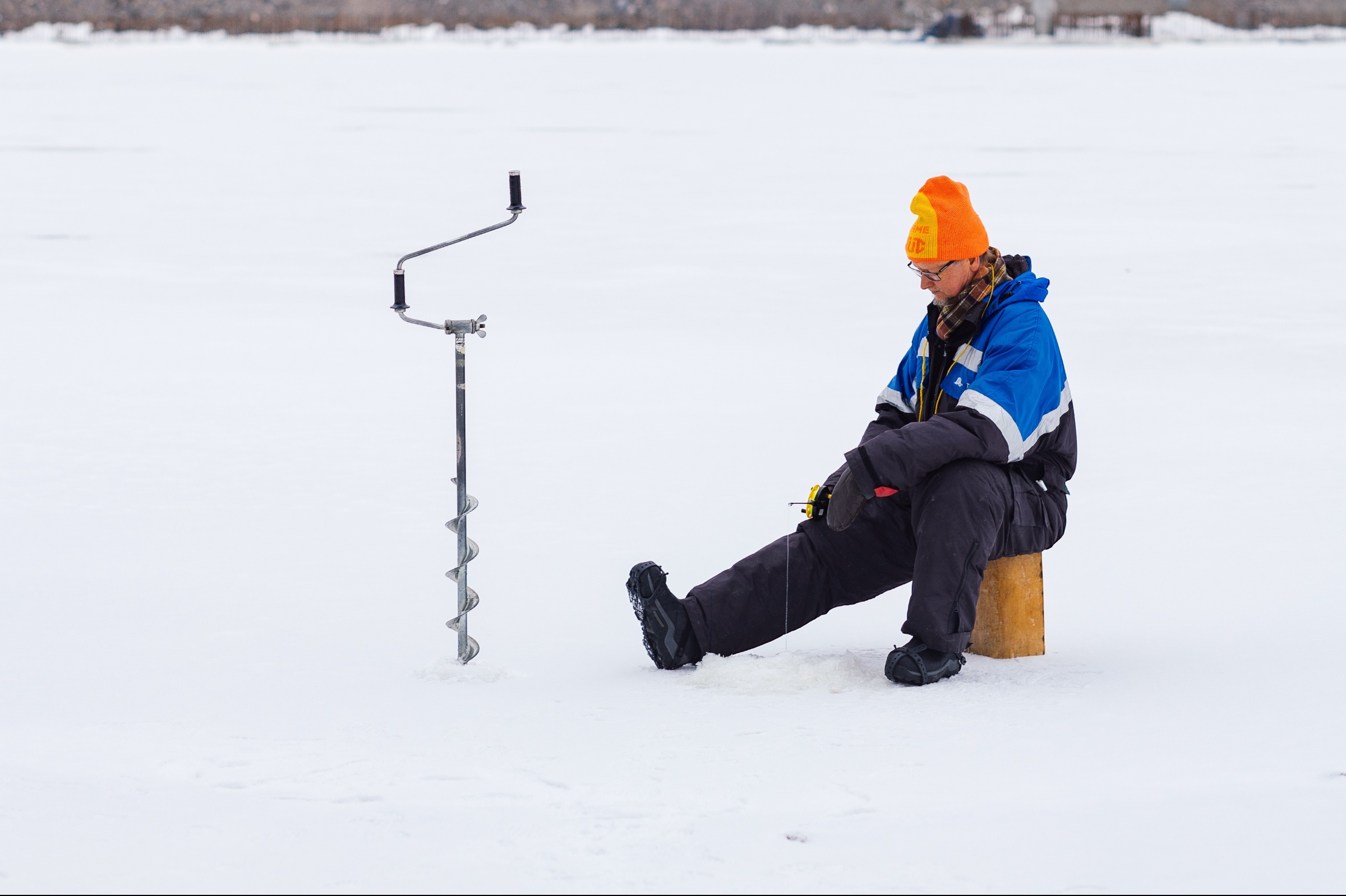 Mies istuu pilkkimässä jäällä vieressään kaira