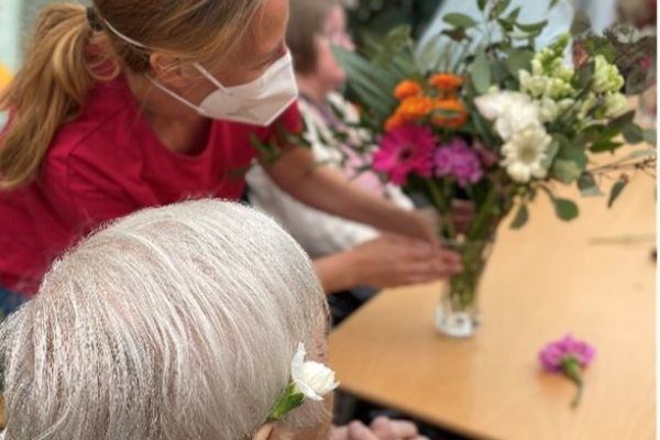 Vapaaehtoinen näyttää kuvassa seniorille yhdessä tehtyä kukkakimppua.